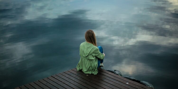 woman sitting on dock near body of water