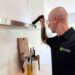 man using a flashlight to inspect cabinet